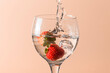 The strawberry falls into the glass and splashes, the bottom is uniform and salmon-colored.
