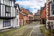 Empty cobbled street lined with brick houses in a city centre on a partly cloudy summer day
