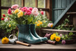 Rubber boots, gardening tools and spring flowers on the wooden terrace in the spring garden