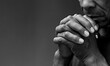 © herlanzer - black man praying to god Caribbean man praying with black background with people stock photo