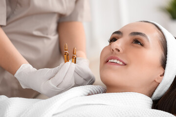 Poster - Beautiful young woman and cosmetologist with ampules in beauty salon, closeup