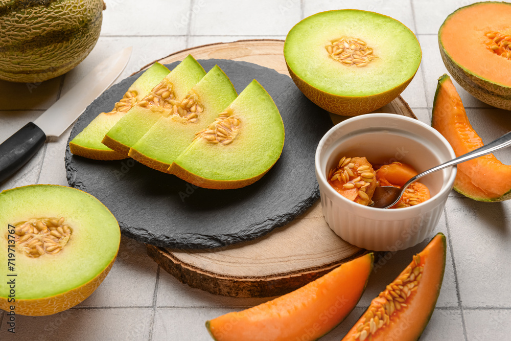 Boards with tasty ripe melons on white tile background