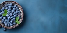 Blueberries In A Ceramic Bowl With Mint Leaves On Dark Blue Surface Background. Generative AI
