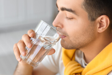 Wall Mural - Young man drinking fresh water in kitchen