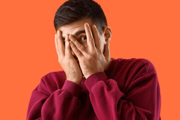 Wall Mural - Afraid young man on orange background