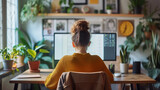 Fototapeta  - Female graphic designer focused on work at a cozy home office with dual monitors surrounded by green plants