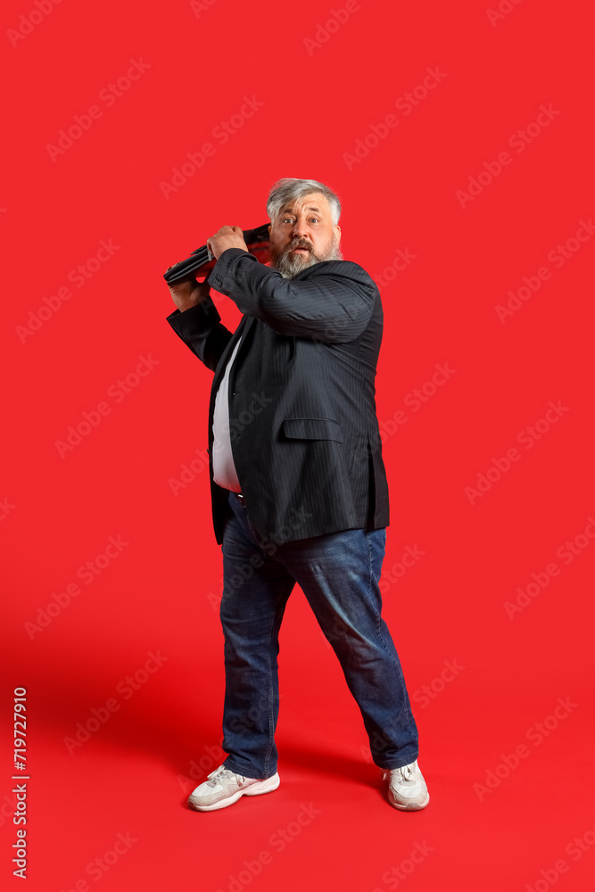 Afraid mature man with briefcase on red background