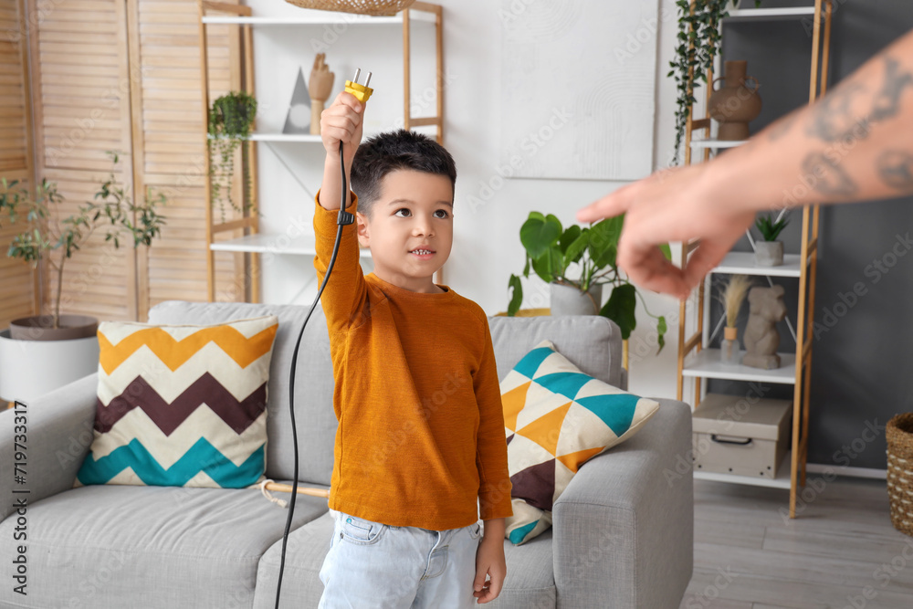 Little boy with vacuum cleaner's plug and his father at home