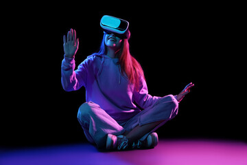 Wall Mural - Young woman using VR glasses on dark background