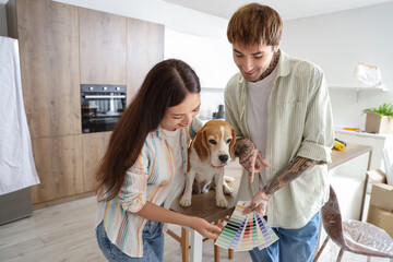 Wall Mural - Young couple with paint color palettes and Beagle dog during repair in their new house