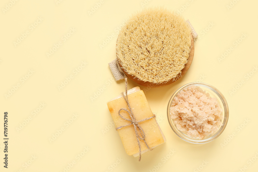 Scrub with soap and brush on light yellow background. Body massage concept