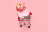Fototapeta Mapy - Small shopping cart with paper bag and flower on pink background. Valentine's Day celebration