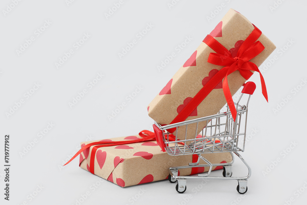 Small shopping cart with gift boxes on white background. Valentine's Day celebration