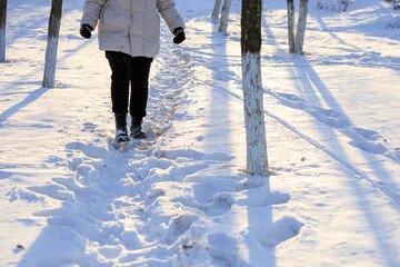 Wall Mural - Woman's legs in winter boots walking in the snow. Background with selective focus and copy space