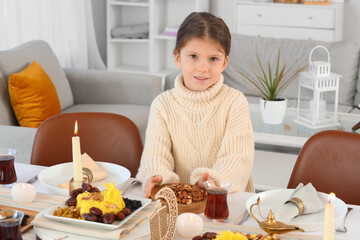 Wall Mural - Little Muslim girl having dinner at home. Ramadan celebration