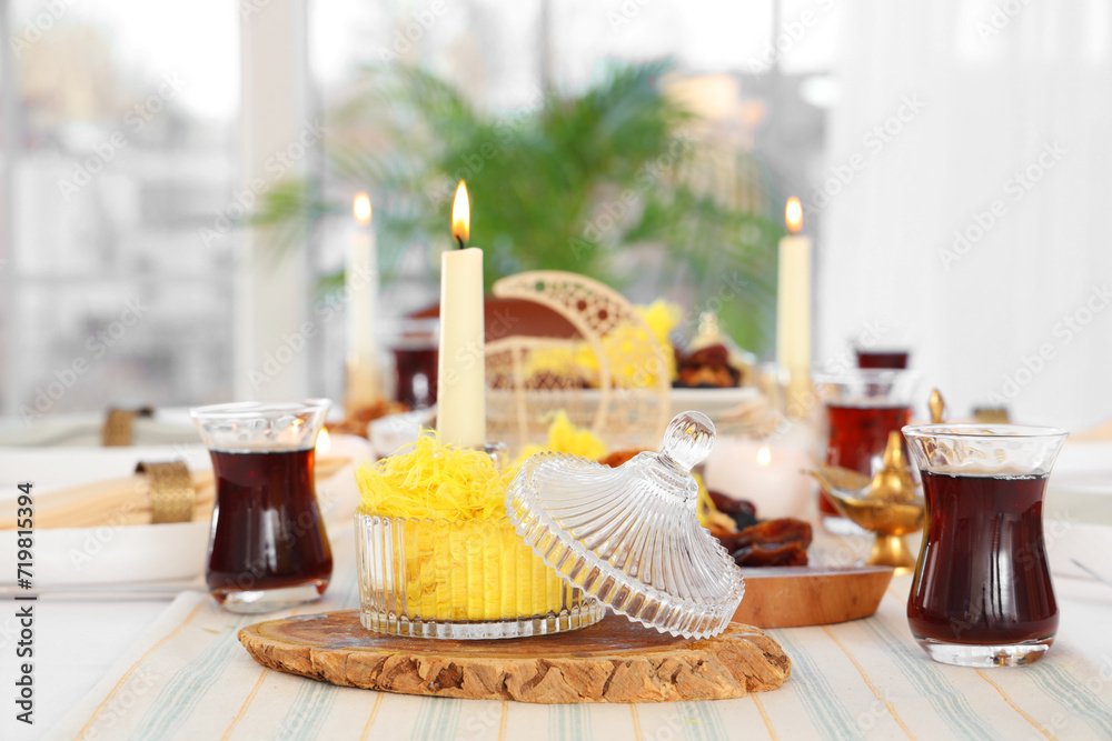 Table setting with traditional Eastern dishes and burning candles for Ramadan in room, closeup