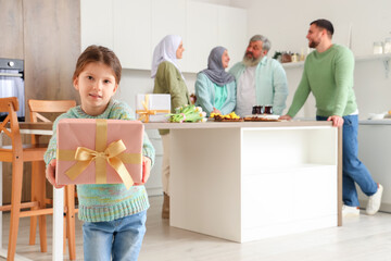 Wall Mural - Little Muslim girl with gift and her family in kitchen. Ramadan celebration