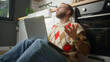 © mahirkart - Man sitting on the floor in kitchen using laptop having anxiety and stress. Upset man reacting to loss, bad news