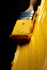 Aufkleber - A person holding a paint brush over a container of yellow paint. This image can be used for various art and painting-related projects