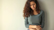Worried young woman holding her stomach.