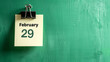 Note on green wall background with written February 29 as a reminder for leap year day with copy space