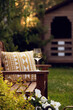 evening relax in cottage summer garden with glass of wine. Wooden bench decorated with cozy pillow and rustic house on background.
