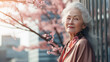 Modern happy smiling elderly woman with gray hair against the background of pink cherry blossoms and metropolis city.