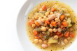 Piatto di saporita minestra con ortaggi vari: ceci, fagioli, patate, carote, sedano, fagiolini e cavolo, cibo vegetariano 