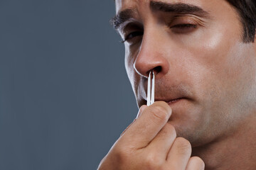 Canvas Print - Man, nose and hair with tweezers for cleaning on grey background for self care, wellness or hygiene. Male person, face and grooming for cosmetic beauty for healthy routine, studio or mockup space