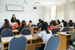 © EduLife Photos - Rearview of university students listen to lecturer explaining lesson in the classroom