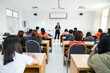 © EduLife Photos - Rearview of university students listen to lecturer explaining lesson in the classroom