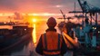Sea or ocean port ships and containers at sunset with backview of an engineer worker wearing orange safety vest and hard hat