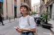 © PhotoBook - Woman with stylish short hair texting on smartphone outside