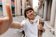 © PhotoBook - Happy excited girl with wonderful smile is holding notes making selfie on city street