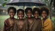group of smiling african children huddled under colorful umbrella in pouring rain - climate change concept