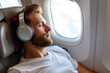 © Evgeniia - A man sleeps on a plane seat near the window. Relaxation on the plane.