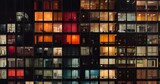 Fototapeta Londyn - Outdoor nighttime photograph of the façade of a large apartment building with a grid of windows lit up in different colors. From the series “Abstract Architecture,