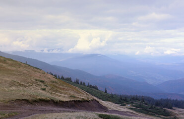 Morning view from the Dragobrat mountain peaks in Carpathian mountains, Ukraine. Cloudy and foggy landscape around Drahobrat Peaks in early morning