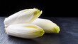 Fresh raw Belgian endives (chicory) on black table, closeup, copyspace on side