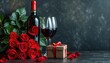 A beautiful bouquet of roses next to a wine divider with a gift box and two wine glasses holding wine
