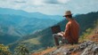 © buraratn - Young man freelancer traveler wearing hat anywhere working online using laptop and enjoying mountains view