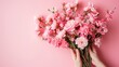 A skilled florist delicately arranges a vibrant bouquet of pink flowers, showcasing the artistry of floral design against a backdrop of a blooming rose garden