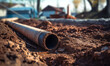 © Natali - A detailed view of a pipes partially buried in the dirt. This image can be used to depict construction, plumbing, or infrastructure projects