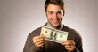 Handsome young man holding a lot of money, on gray background