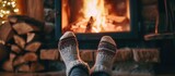 Fototapeta  - Woman in wool socks warms feet by cozy fire in after ski cabin, closeup of cute legs in cold season.