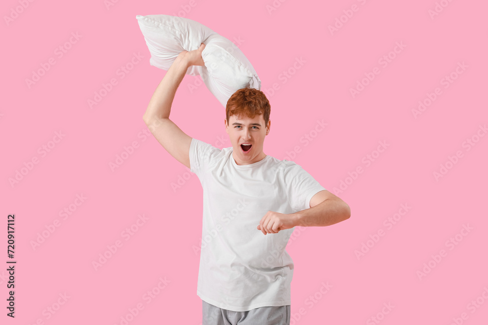 Young man with soft pillow on pink background