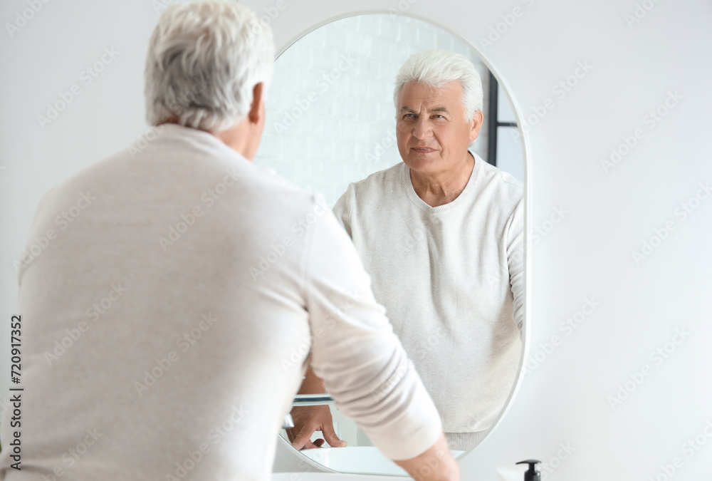 Senior man looking in mirror at home