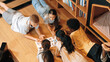 Group of diverse children lying down in circle while reading a book at library. Top view of girl sharing a magazine while pointing at interested topic and talking with lovely friends. Edification.