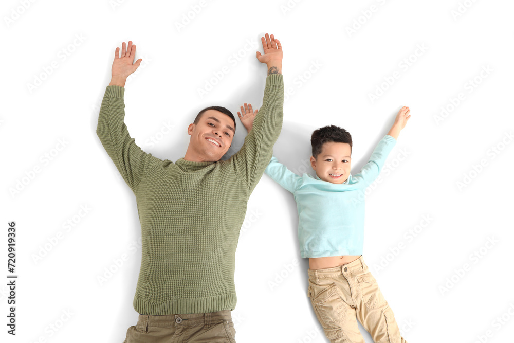 Young man with his little son lying on white background, top view