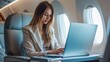 © ETAJOE - Business woman working with laptop at commercial airplane